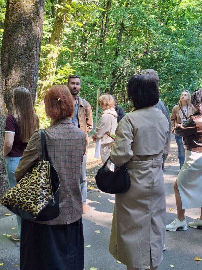 Рассказ среди леса Экскурсовод беседует с группой среди деревьев Покровского-Стрешнева