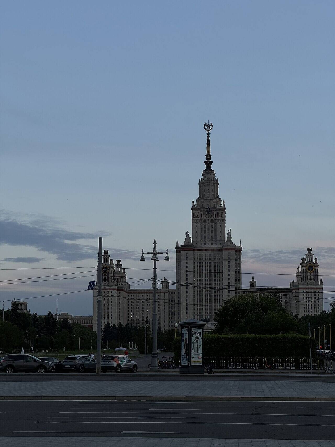 The main building of Moscow State University, with its tall central spire and side towers, beyond a city road.