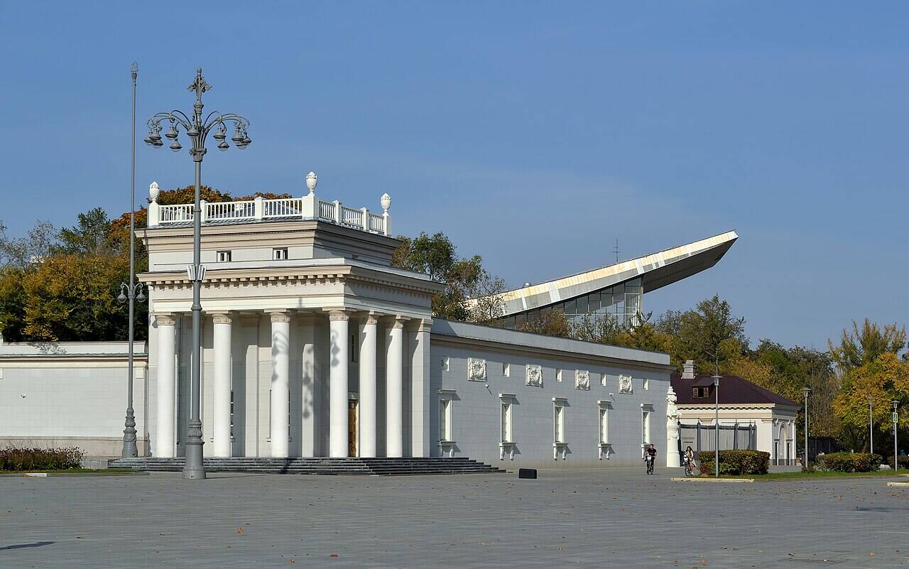 Северное крыло Главного входа ВДНХ, за которым видны стеклянный фасад и изогнутая кровля павильона № 70