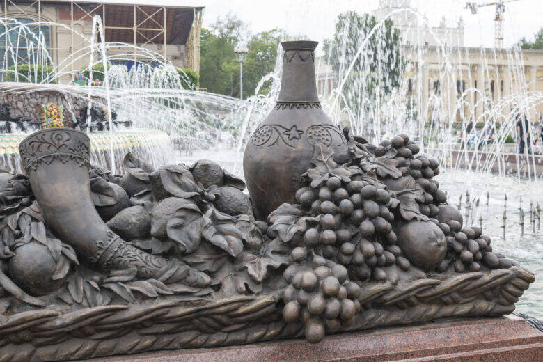 Скульптурный натюрморт с сосудом, гроздьями винограда и плодами на фоне струй фонтана «Каменный цветок»