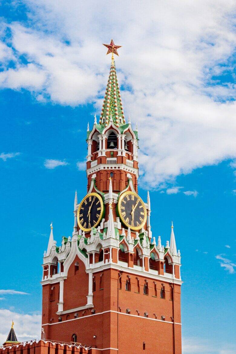 Верхняя часть Спасской башни с часами и звездой на фоне голубого неба.