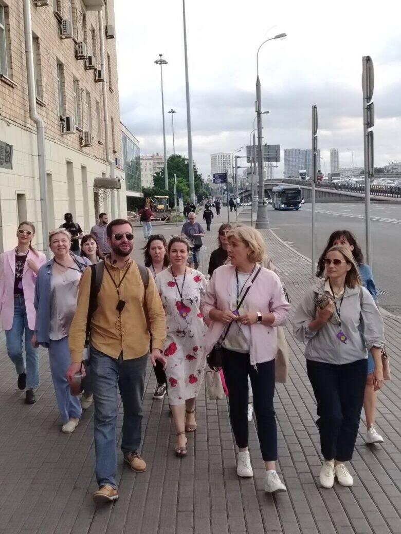 Пешеходная часть корпоративного маршрута Корпоративная группа идёт по городскому тротуару во время прогулки с гидом