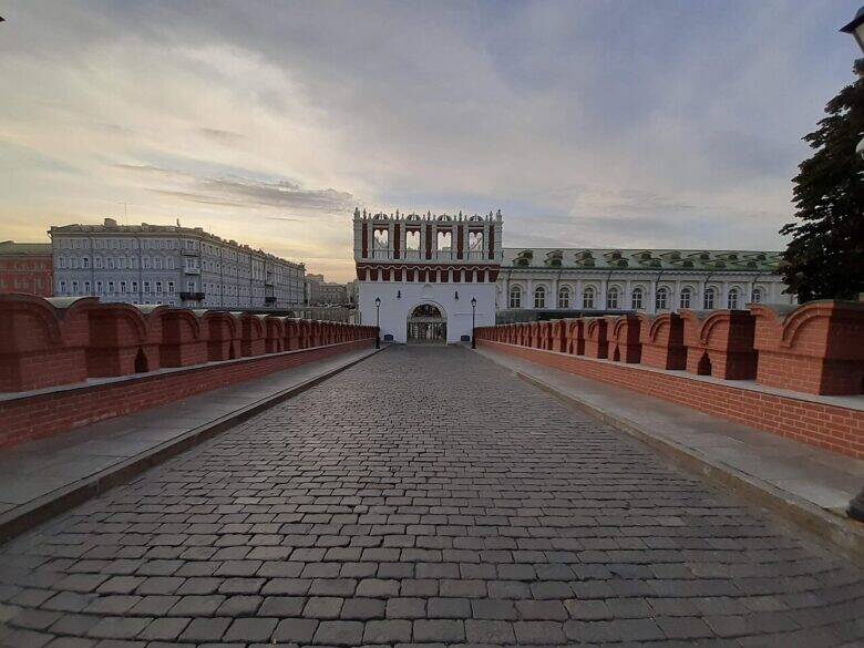 Мощёный Троицкий мост с красными парапетами и башней впереди