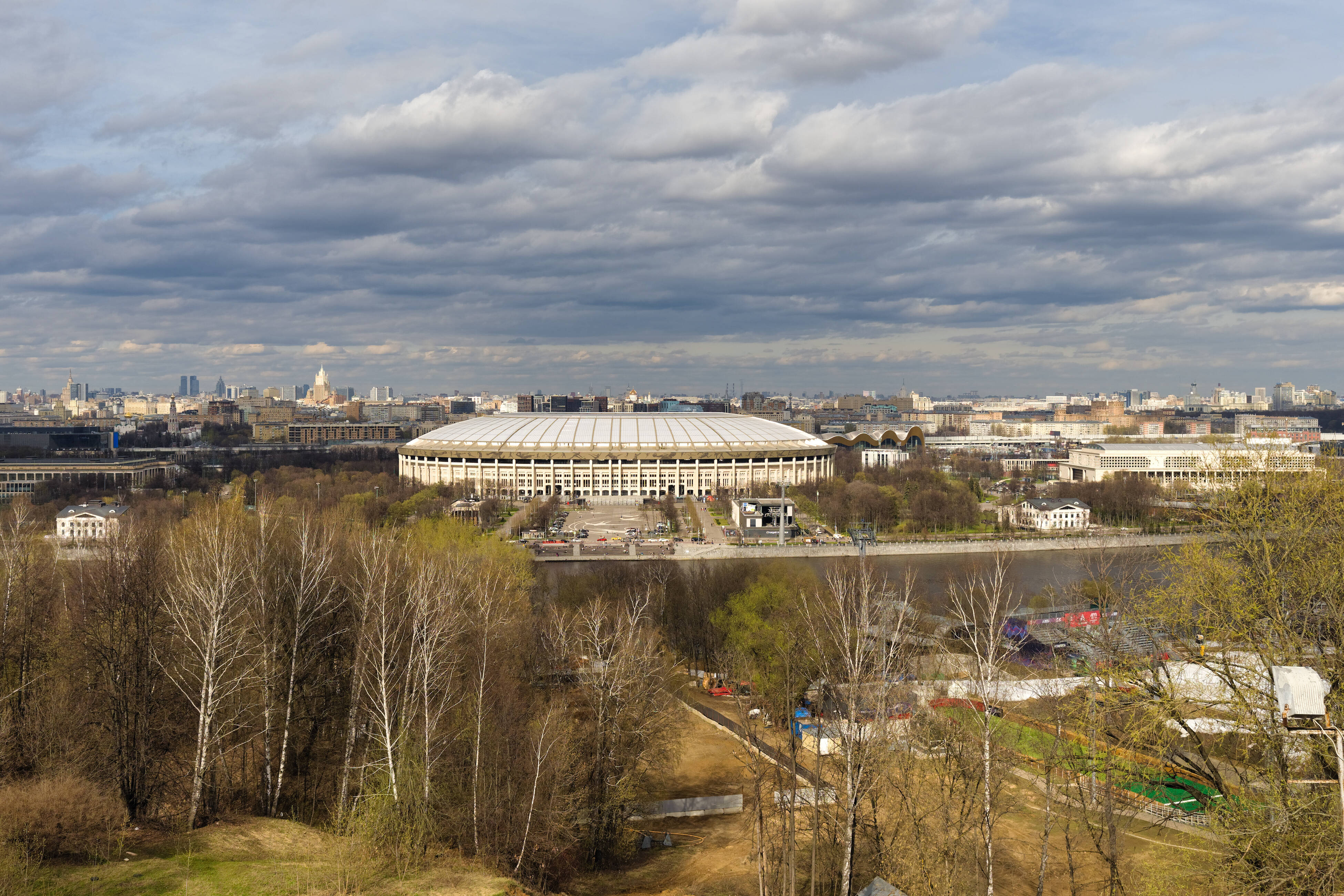 View from Sparrow Hills: trees on the slope, the Moscow River and Luzhniki Stadium beyond it.
