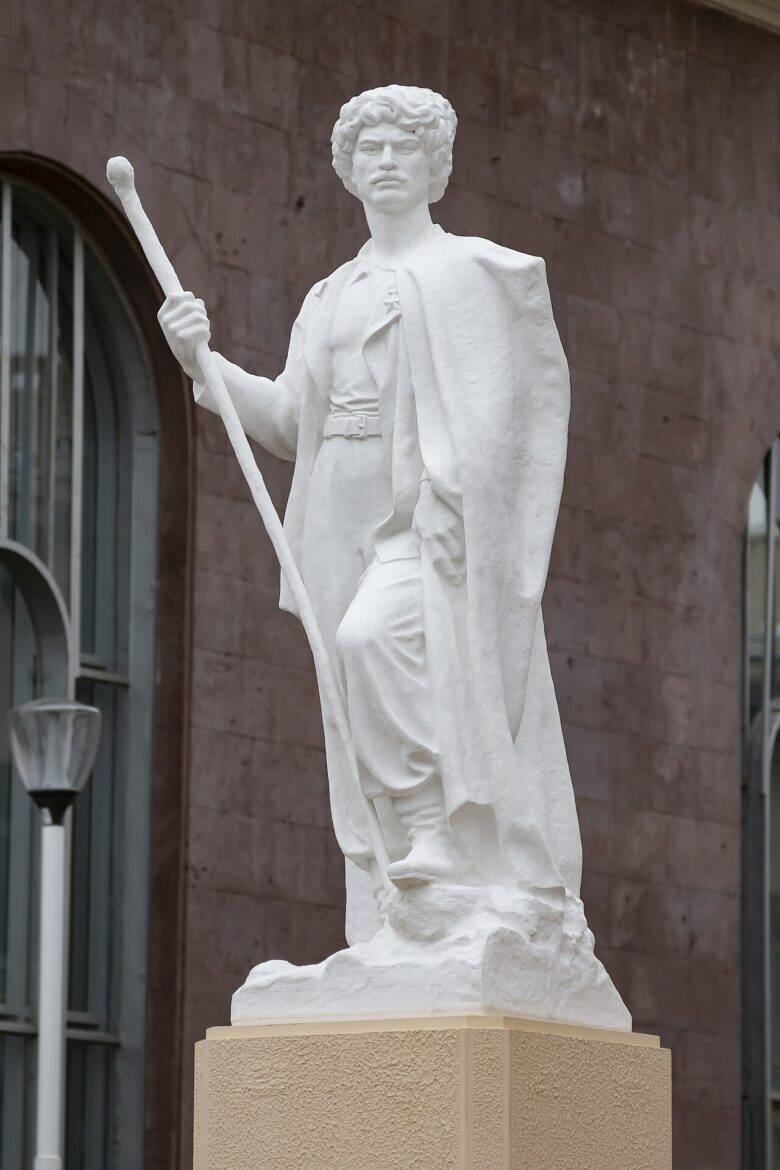 A white sculpture of a shepherd with a staff, standing on a pedestal beside Pavilion No. 14.