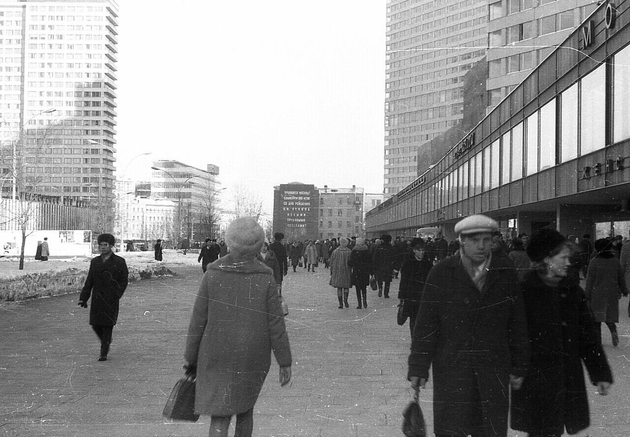 Pedestrians near the shopping strip on Kalinin Prospekt, with high-rise buildings visible on the left