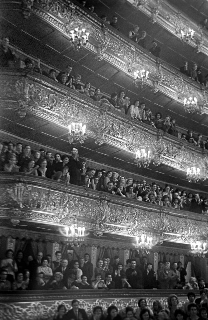 Чёрно-белая фотография зрителей в нескольких ярусах лож Большого театра.
