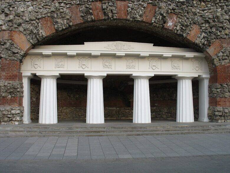 A white portico with four columns in a deep recess beneath the grotto’s stone-and-brick arch