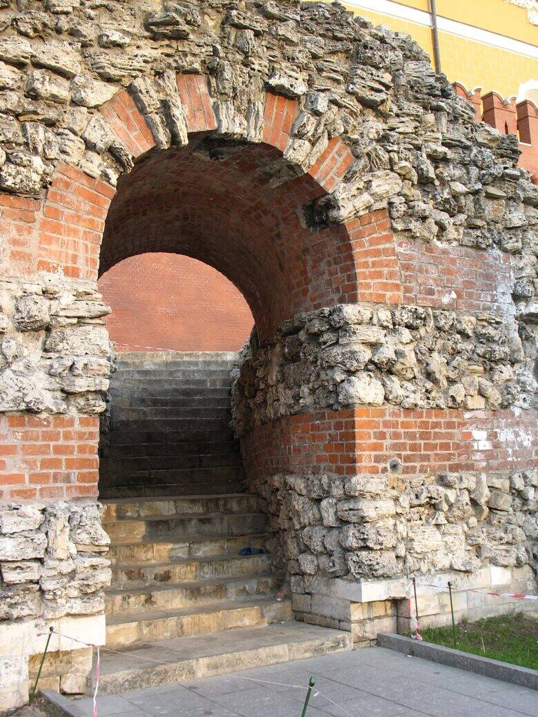 A brick arch within the grotto’s stonework; a staircase rises behind it.