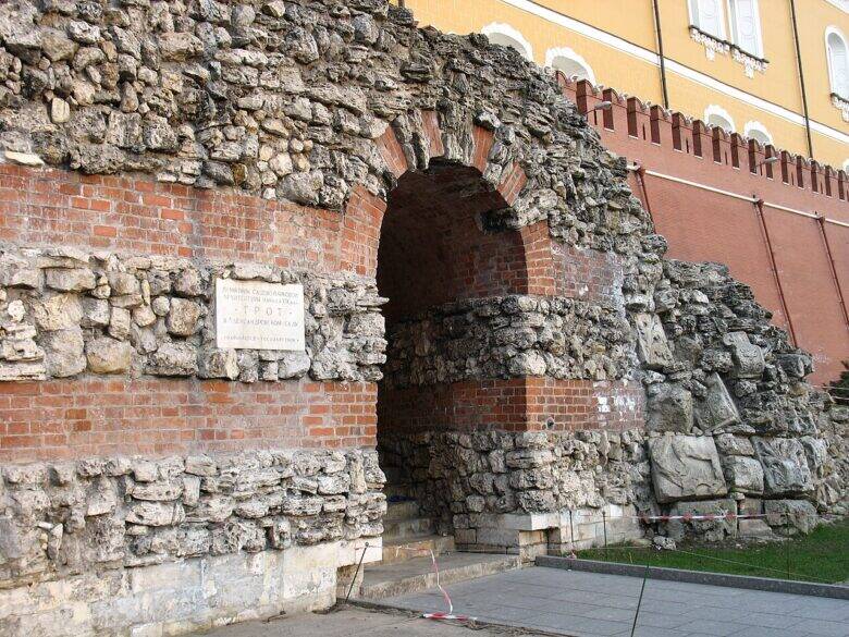 Arched passage through the grotto’s brick and stone masonry; the crenellated Kremlin wall behind.