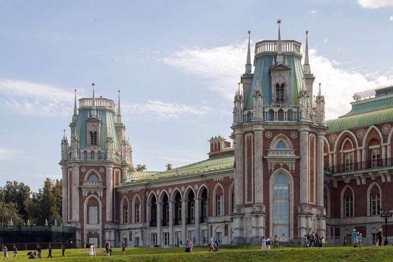 The Grand Palace at Tsaritsyno with two towers and an arcade; visitors stroll in front of the façade.