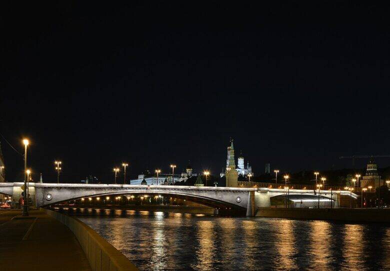 The illuminated Bolshoy Moskvoretsky Bridge crosses the Moskva River; the Kremlin towers are visible in the background.