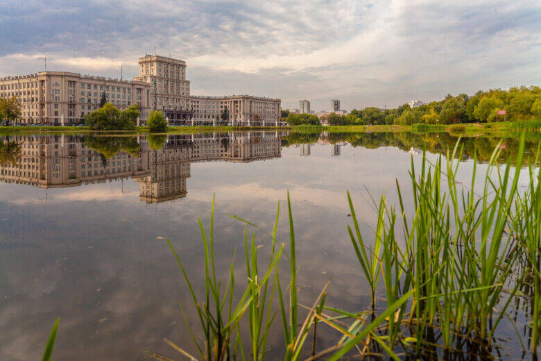 A broad pond with reeds along the bank; across the water stands a building of Bauman Moscow State Technical University with a central tower.