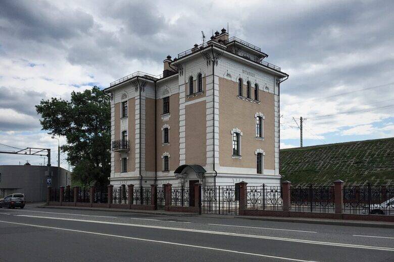 围栏后是原波特利哈停靠站的浅色多层建筑，前方是一条道路。