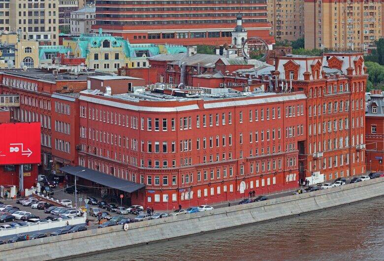 The red-brick buildings of the former Krasny Oktyabr factory along Bersenevskaya Embankment, photographed from an elevated viewpoint across the Moskva River.