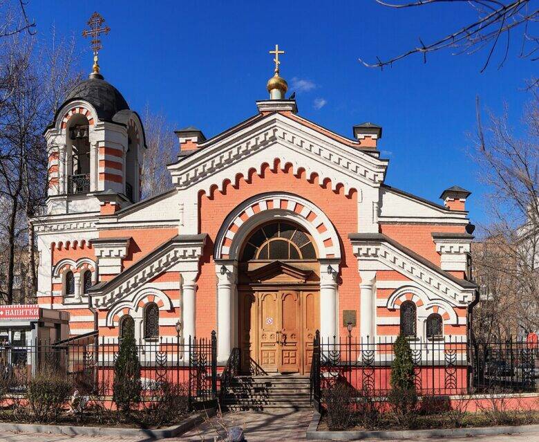 Фронтальный вид красно-белой часовни Архангела Михаила с арочным входом и звонницей.