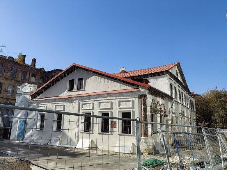 Anna Mons’s House with red pitched roofs and pale façades behind construction fencing.