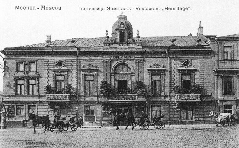 A black-and-white postcard showing the façade of Moscow’s Hermitage Hotel and Restaurant, with horse-drawn carriages in front of the building.