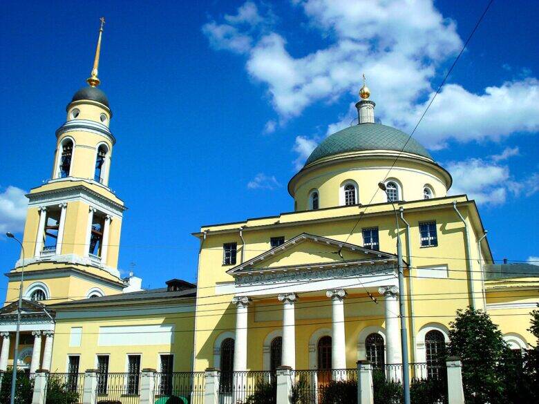 The yellow Church of the Greater Ascension, with a columned portico, dome and bell tower.