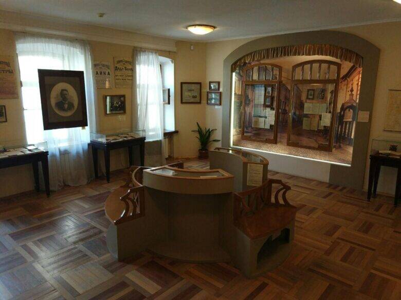 A room in the Chekhov Museum with a portrait by the window, display panels and glass cases