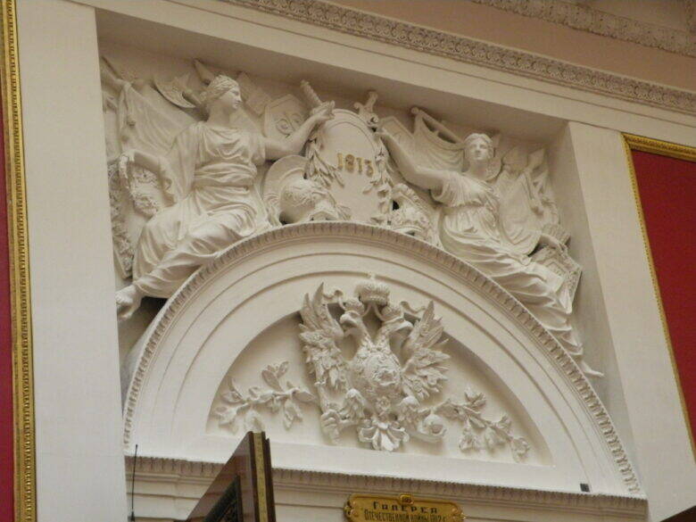 White stucco decoration above an arch: two female figures, a double-headed eagle and the date ‘1813’.