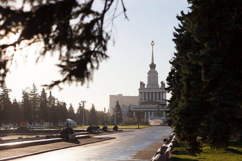 A general view of an avenue at VDNKh: the edge of a drained pool is visible on the left, with a pavilion topped by a spire in the distance.