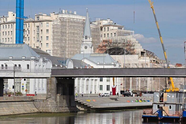 A bridge span over the canal, the embankment, buildings clad in scaffolding and a construction crane