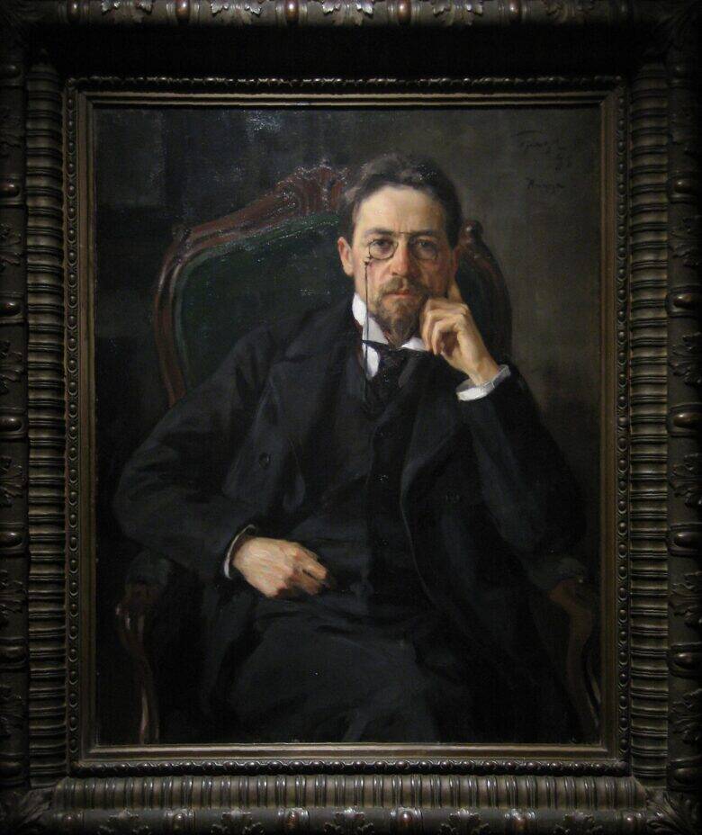 A portrait of Anton Chekhov in a carved frame: the writer sits in an armchair wearing a dark suit, resting his cheek on his hand.