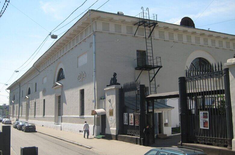 The pale façade of the Provision Warehouses along the street and tall black gates at the entrance.
