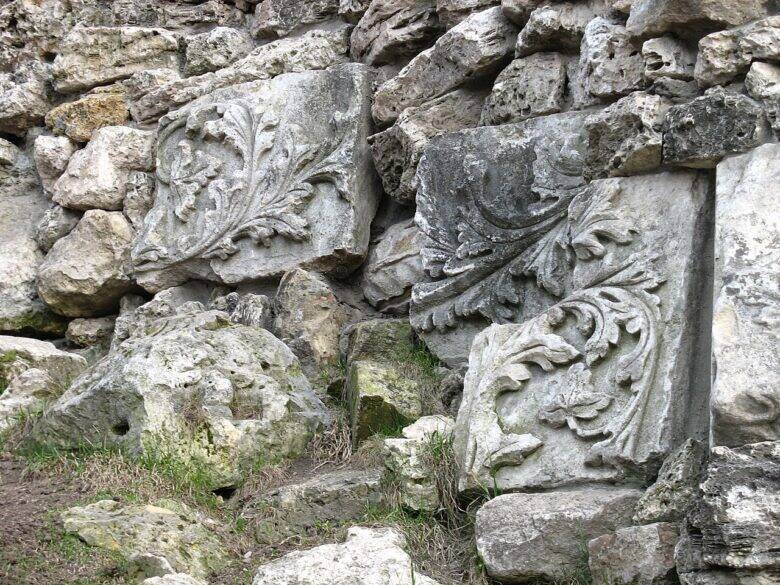 Two stone fragments with floral ornamentation set among the grotto’s uneven masonry.