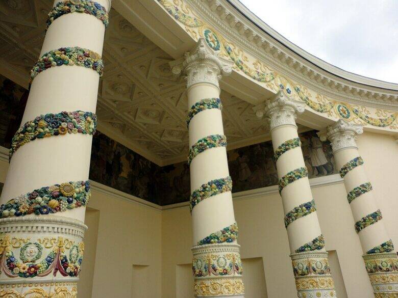 The curved colonnade of the Belarus Pavilion at VDNKh; a mural is visible behind the decorated columns.