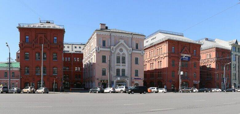 A group of red façades and one pale façade on Novaya Square, across a wide road
