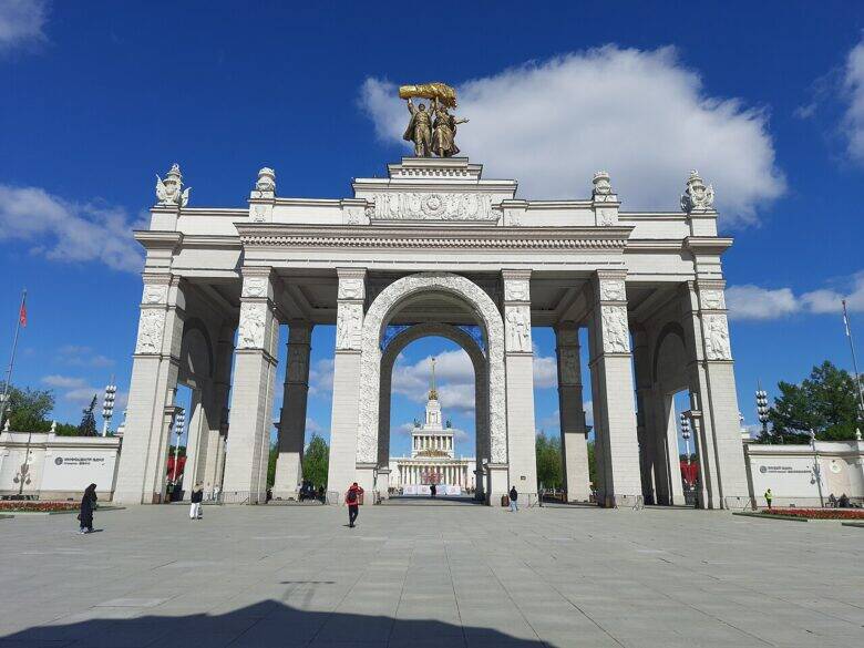 The white Main Entrance arch at VDNKh, with two figures holding a sheaf aloft above the central opening.