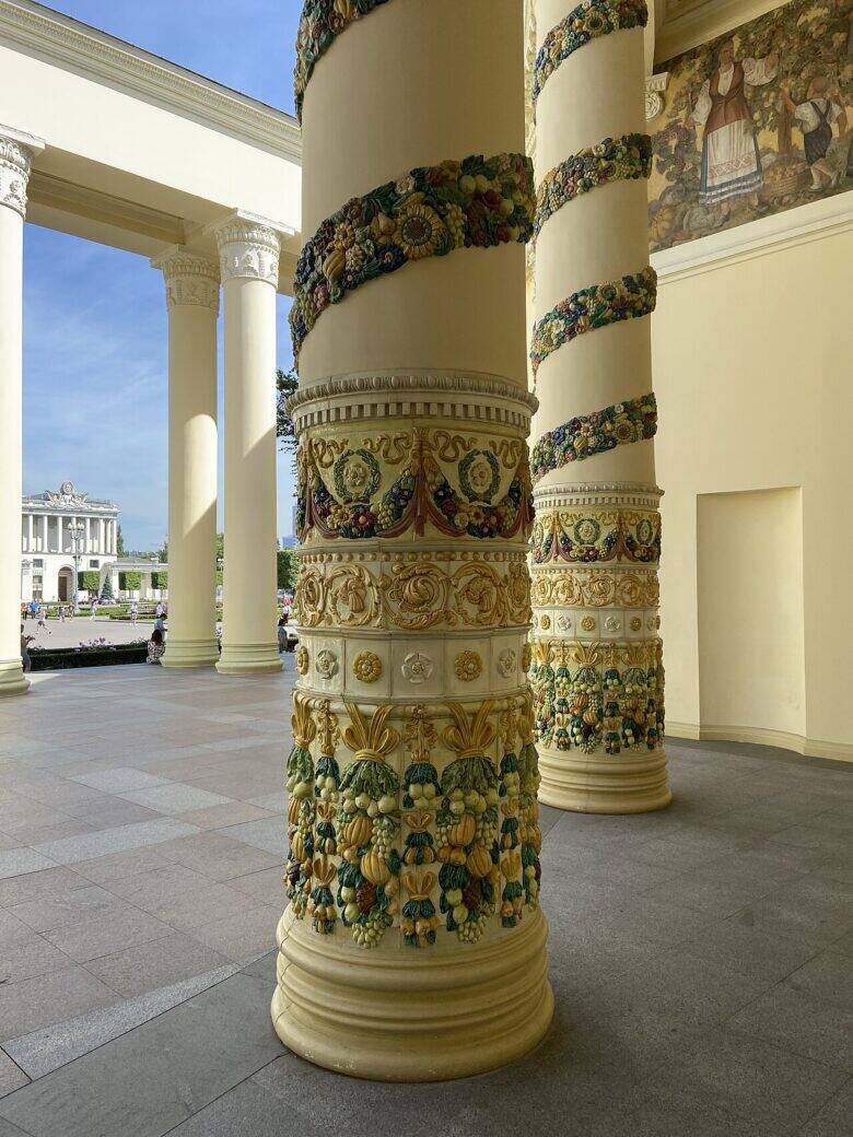 A column with colourful botanical garlands and reliefs at the pavilion entrance.
