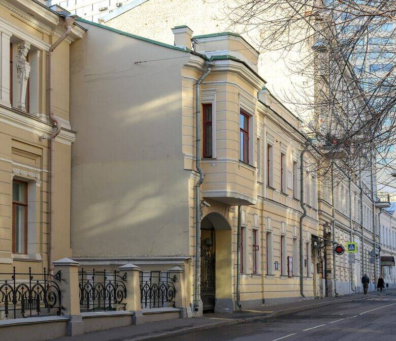 The pale façade of the Scriabin Museum with a bay window and an arched passageway along the street