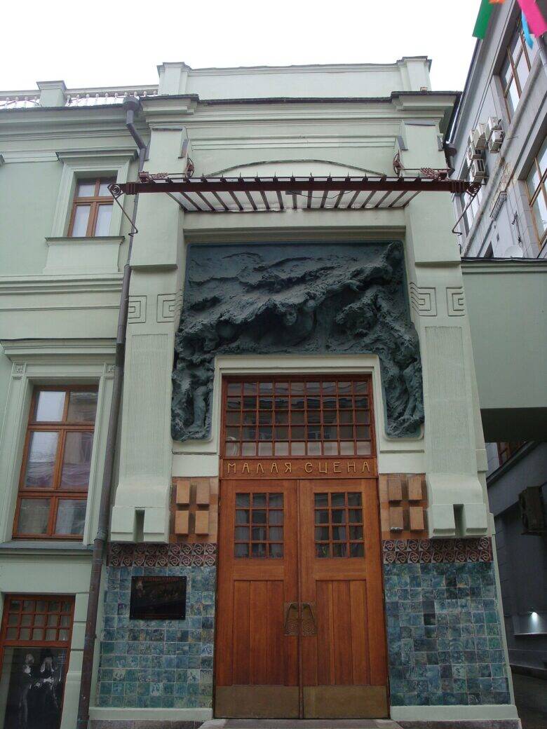 The theatre’s light-coloured façade, the wooden doors to the Small Stage and a bas-relief above the entrance.