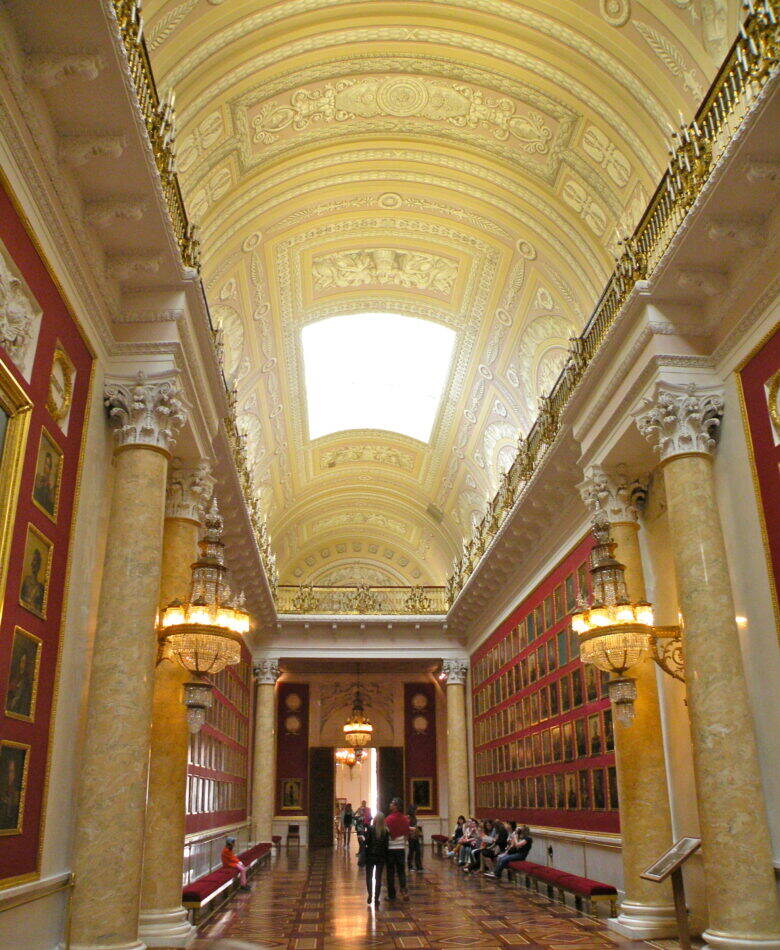 The long hall of the Military Gallery in the Winter Palace, with rows of portraits on red walls.