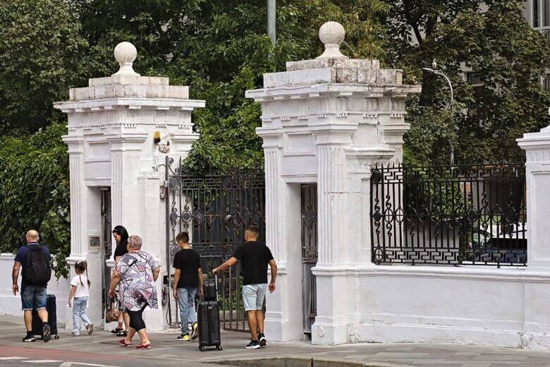 White gateposts and a black metal fence outside No. 17 Bolshaya Ordynka; pedestrians walk past them.